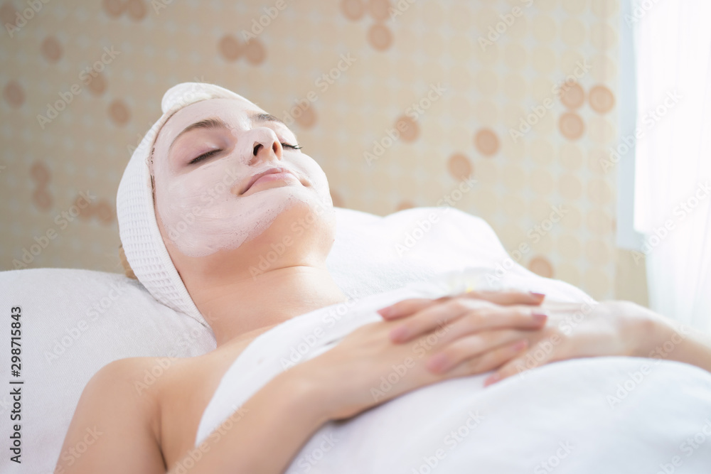Facial mask massage. Attractive beautiful young woman relax lying on massage bed, Beautician is applying facial cream on his skin. Spa aroma therapy and massage facial beauty treatment concept.