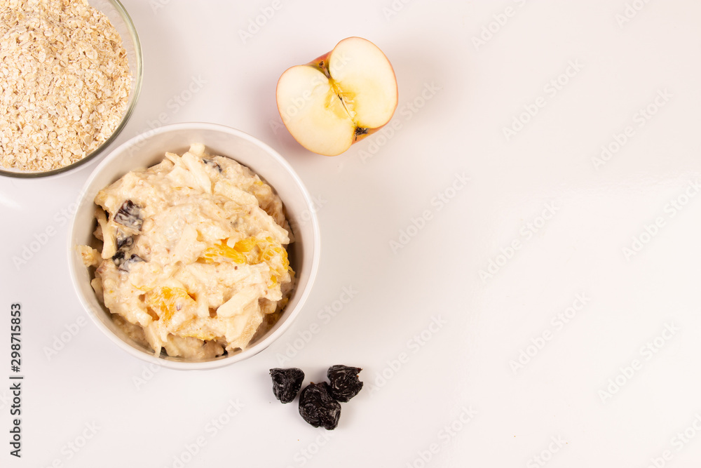 Salad of apple, orange, oat hops and prunes with honey in a white plate on a white background. Salad of apple, orange, oat hops and prunes with honey in a white plate on a white background.