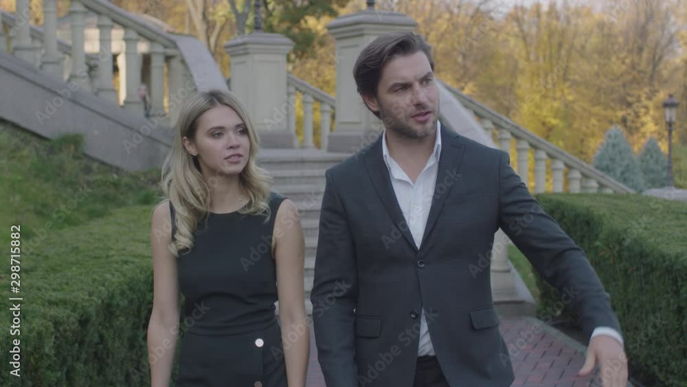Work colleagues walk in the park and communicate. A man tells a girl about something Work colleagues walk in the park and communicate. A man tells a girl about something
