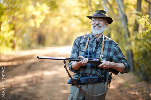 Smiling hunter hold shotgun, posing in forest. Hunting on birds