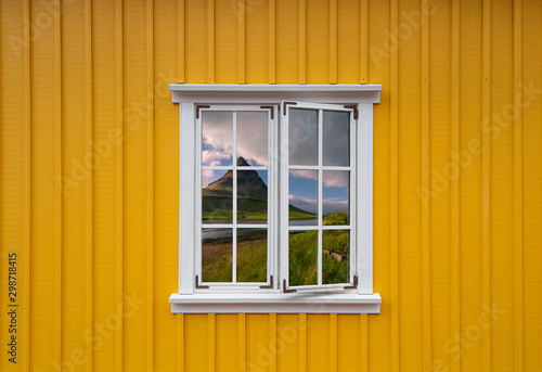 Obraz na płótnie Yellow wooden house with a white window with a reflection of the Icelandic landscape w salonie