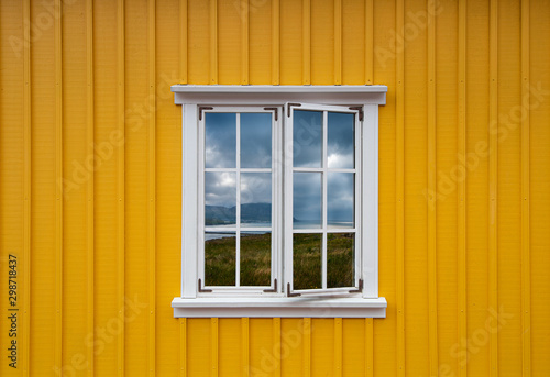 Typical icelandic yellow house with white frame and landscape reflection