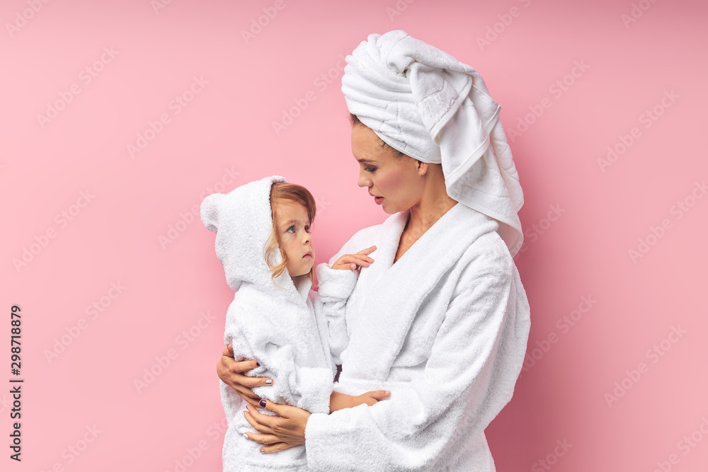 After taking bath, mother and her daughter in bathrobe and towel.isolated pink background After taking bath, mother and her daughter in bathrobe and towel.isolated pink background