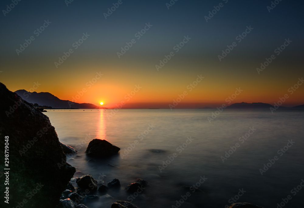 Panorama of beautiful sunrise at Kos. Stones in front of sunrise.