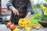 Autumn traditions and preparations for the holiday Halloween. A house in nature, a lamp made of pumpkins is cutting out at the table.