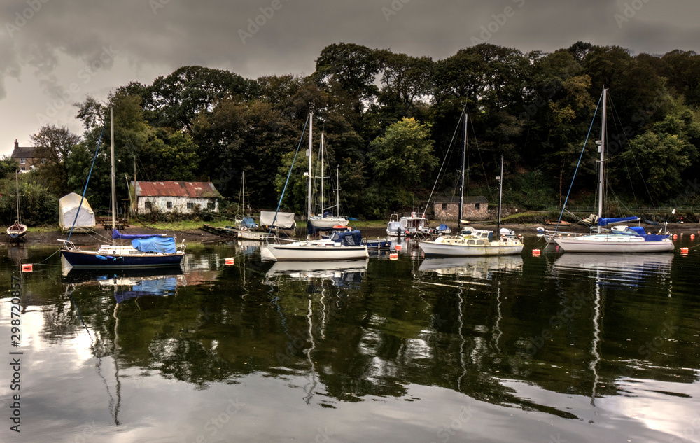 Abandoned boat house with yachts moored alongside the river estury