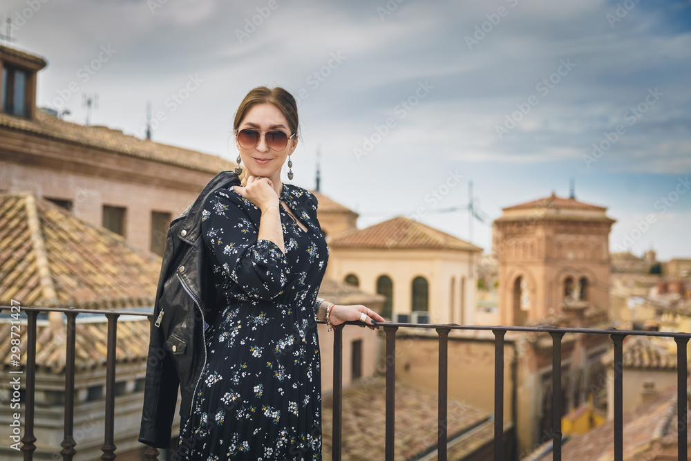 Stylish woman posing in the old part of the town against tile roofs. Medieval city of Toledo in the center of Spain.