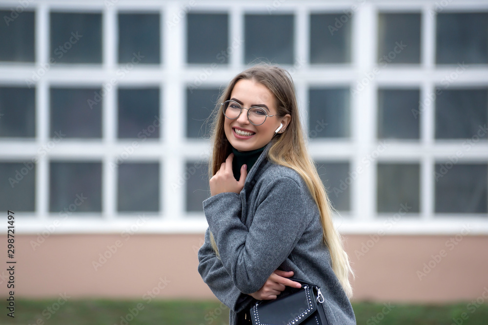 Fototapeta premium Young beautiful blonde with glasses on the city streets.