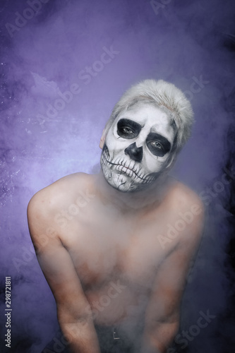 portrait of a man with halloween face art make up alone in the dark background