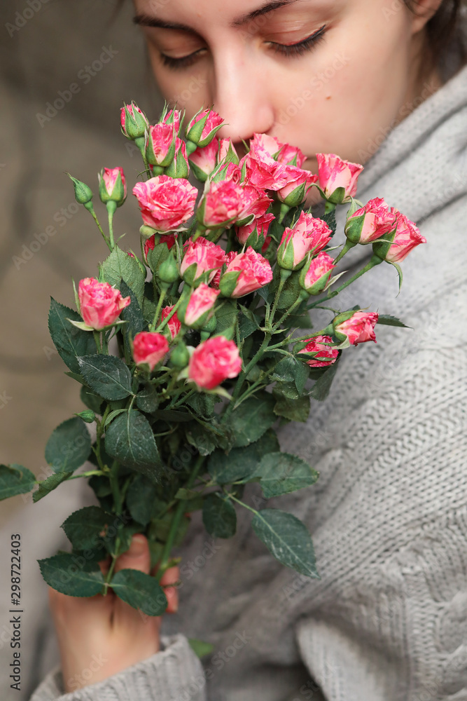 bouquet of bush of roses in female hands on a background