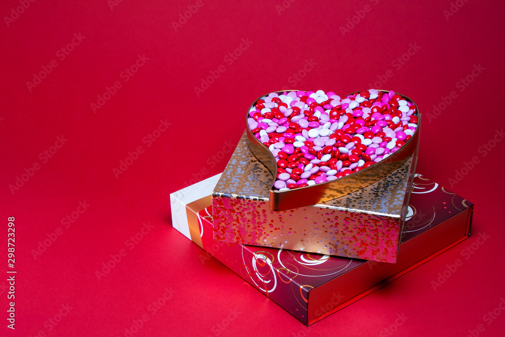 Heart shaped box filled with pink and white coated candy on top of a ...