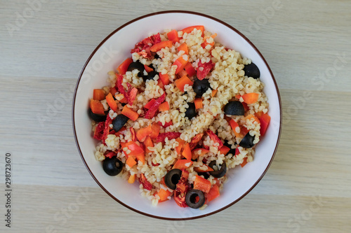 Bulgur Salad wiht different vegetables in a bowl on wooden background