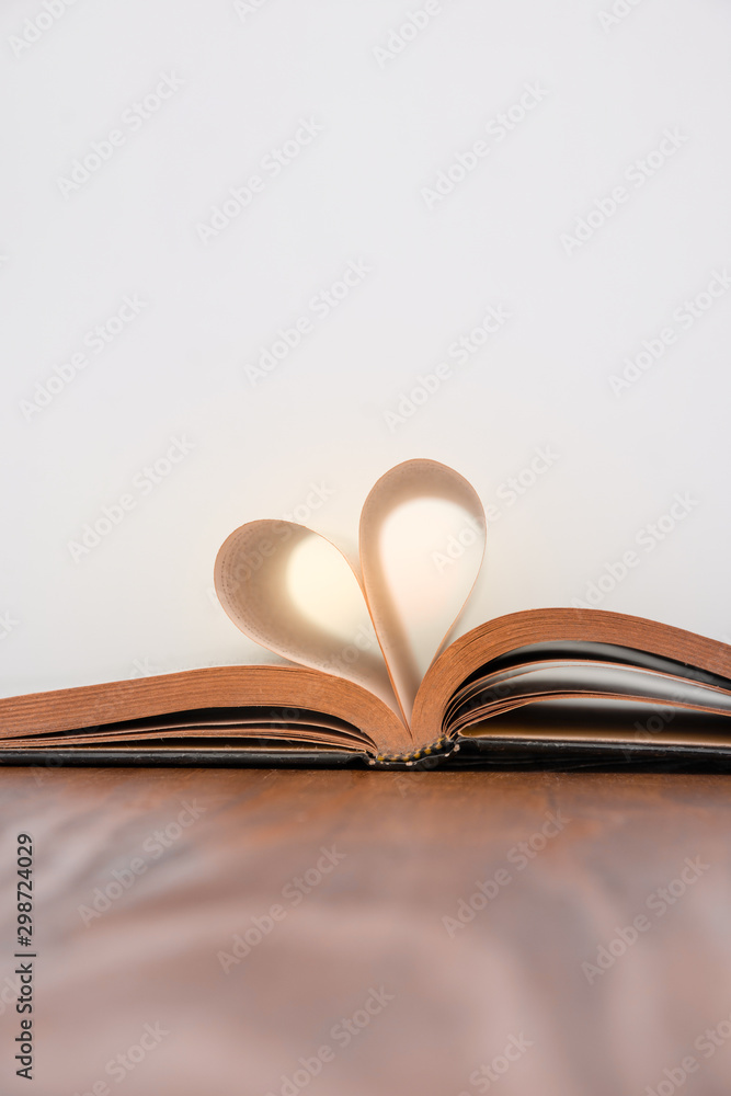 Old book and heart-shaped pages. White background. Wooden Table. Copy space Old book and heart-shaped pages. White background. Wooden Table. Copy space
