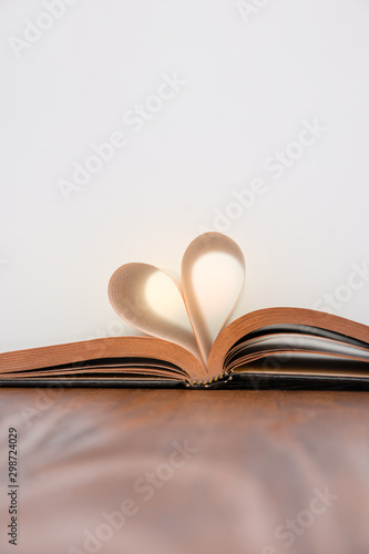 Old book and heart-shaped pages. White background. Wooden Table. Copy space