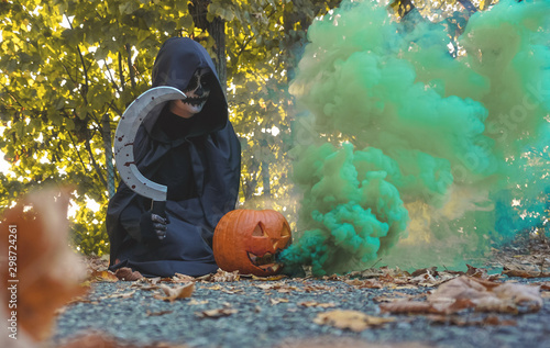 Black costume for halloween- Women with bloody sickle in forest- Scary whitch doing a spell with magical pumpkin in green smoke