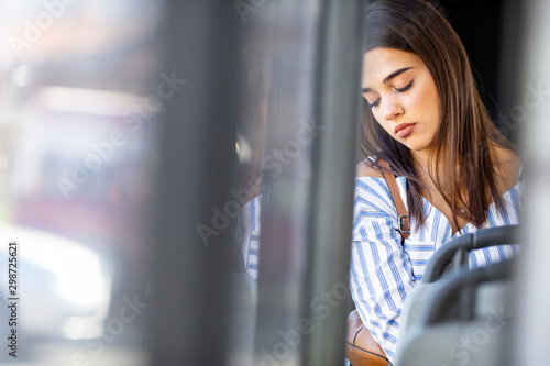  Young lady passenger Sitting in depressed mood beside the window inside Bus which travel between town when travel alone for escape the chaos, traveller and depress concept.
