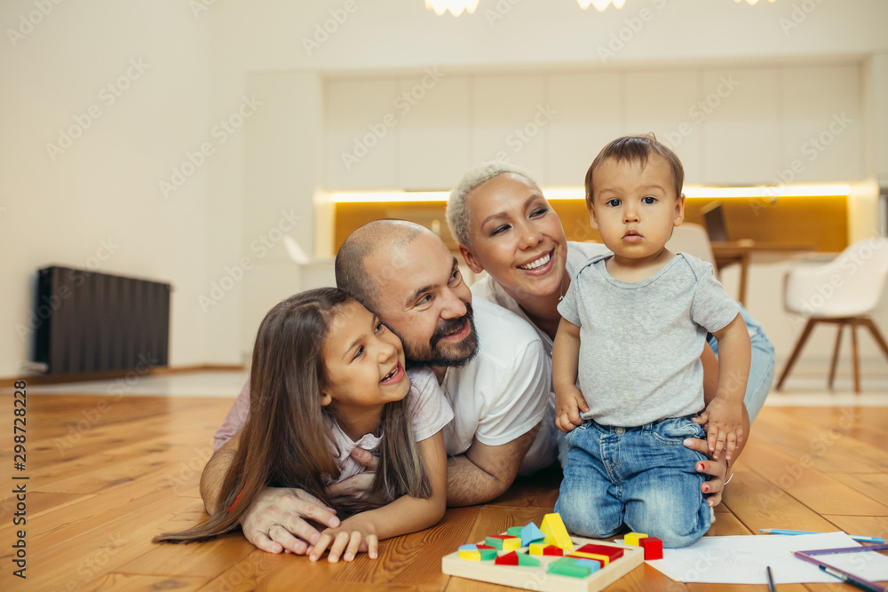 Positive family happy together on floor. Portrait of caucasian family lying, smiling. Happy family concept Positive family happy together on floor. Portrait of caucasian family lying, smiling. Happy family concept