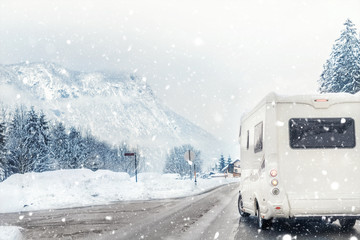 Caravan or campervan turning from road with beautiful mountain alpine landscape on background at cold winter season.Family vacation travel, holiday trip in motorhome. Beautiful austrian nature scene