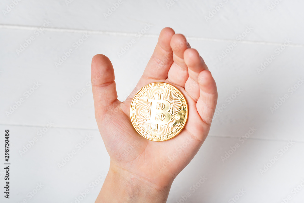 Fototapeta premium Bitcoin coin in a child's hand. Close up.