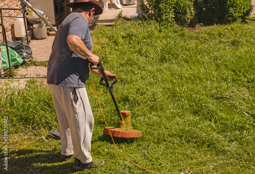 photograph of man cutting grass