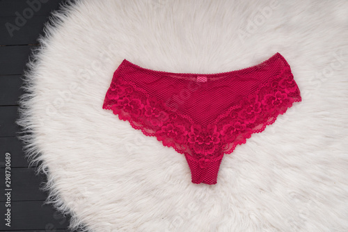 Raspberry lace panties on white fur. Fashionable concept of lingerie