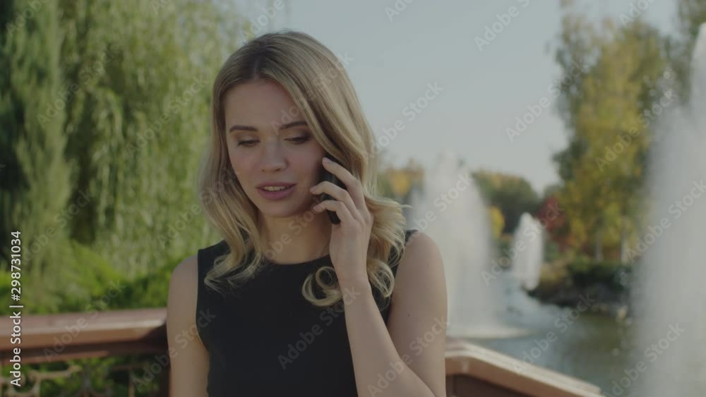 Business woman talking on the phone in a city park. Serious woman Business woman talking on the phone in a city park. Serious woman