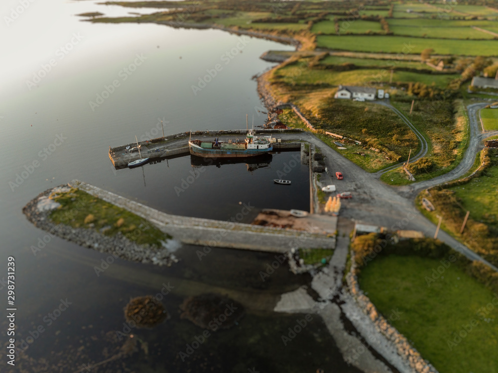 Small harbor with cargo ship and small boats. Aerial view. Kilmacduagh Galway bay. Ireland.