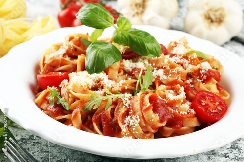 tagliatelle pasta with tomato sauce parmesan basil on rustic background
