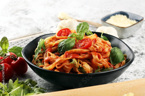 tagliatelle pasta with tomato sauce parmesan basil on rustic background © beats_