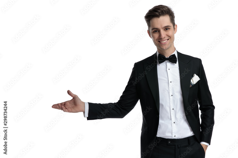 happy young model in tuxedo smiling and presenting to side happy young model in tuxedo smiling and presenting to side