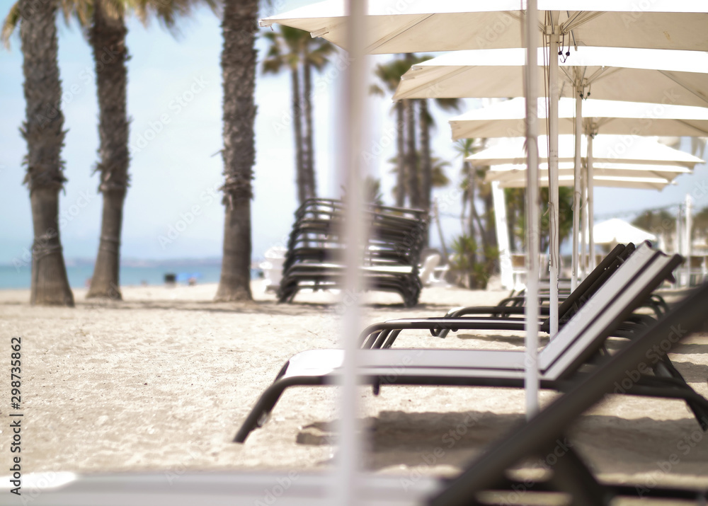 Deserted beach, empty deck chairs under white umbrellas Deserted beach, empty deck chairs under white umbrellas