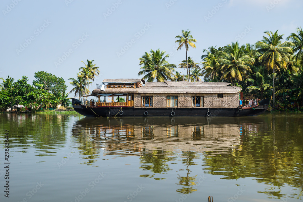 Traditional houseboat in the Kerala backwaters along palm tree ...