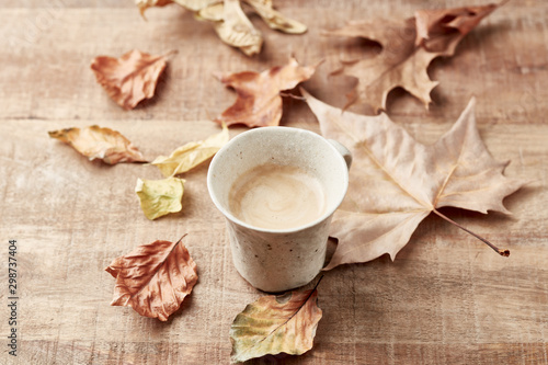 Mug of coffee and autumn leaves. Rustic wooden background. Copy space. 