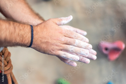 Close up of climber man coating hands in powder chalk magnesium and preparing to climb workout outdoor training rock wall .
