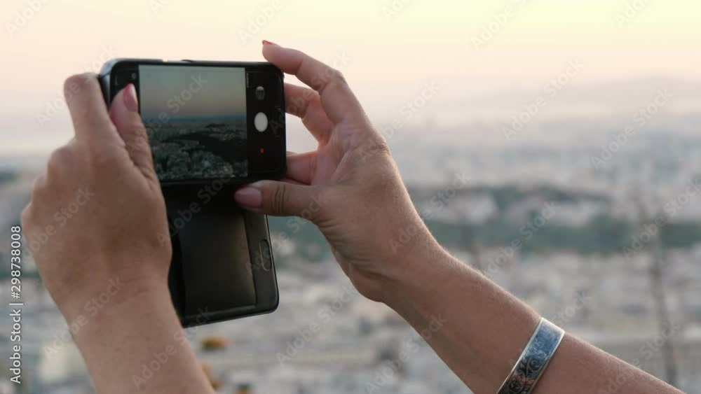 Female hands keeping a smartphone and taking a photo of Athens landscape Female hands keeping a smartphone and taking a photo of Athens landscape