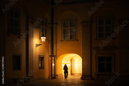 Woman walking thru a old yellow passway during evening hours in the Hofburg palace