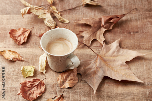 Mug of coffee and autumn leaves. Rustic wooden background. Copy space. 