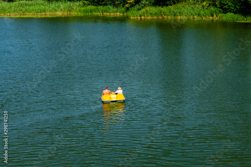 Adult couple driving yellow catamaran on a river