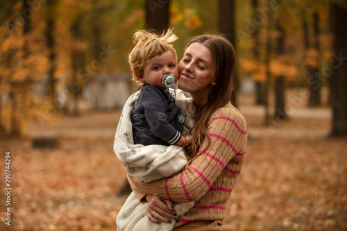 Happy mother with her beautiful baby in the autumn park. Lifestyle. Mom and son.