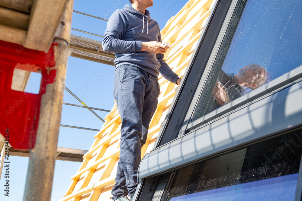 Young carpenter installing a skylight on a wooden roof truss Young carpenter installing a skylight on a wooden roof truss