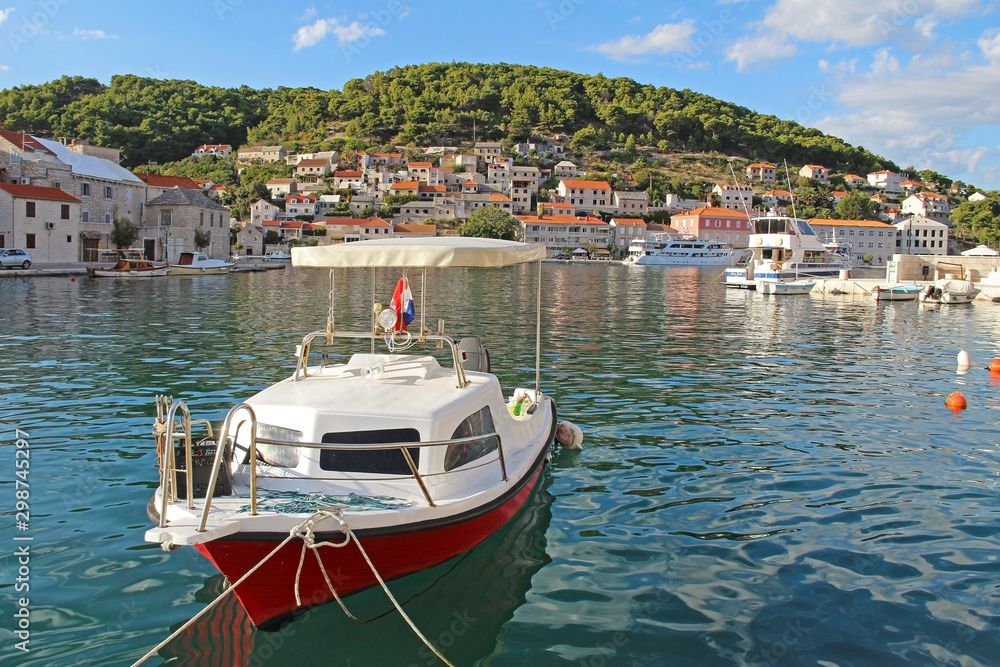 Pucisca, Brac Island, Croatia. Traditional fishing boat in the port. View of the city.