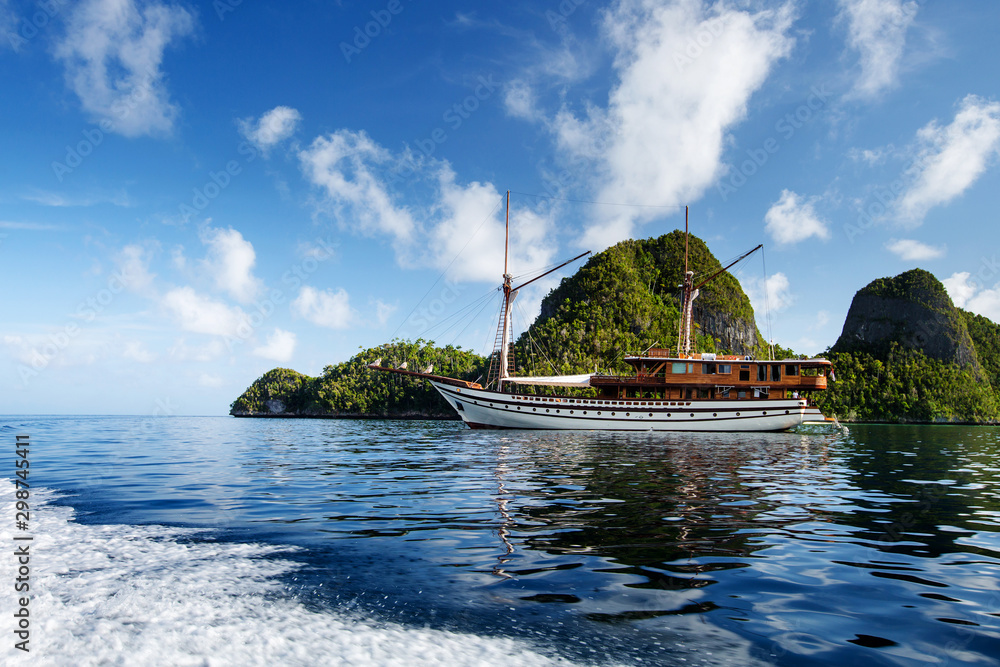 Fototapeta premium Sail boat between islands of remote archipelago Pulau Wayag, Raja Ampat, Indonesia