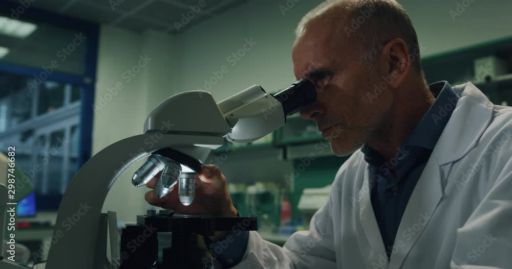 Portrait of male scientist is analyzing a sample to extract the DNA and molecules with microscope in laboratory. Portrait of male scientist is analyzing a sample to extract the DNA and molecules with microscope in laboratory.