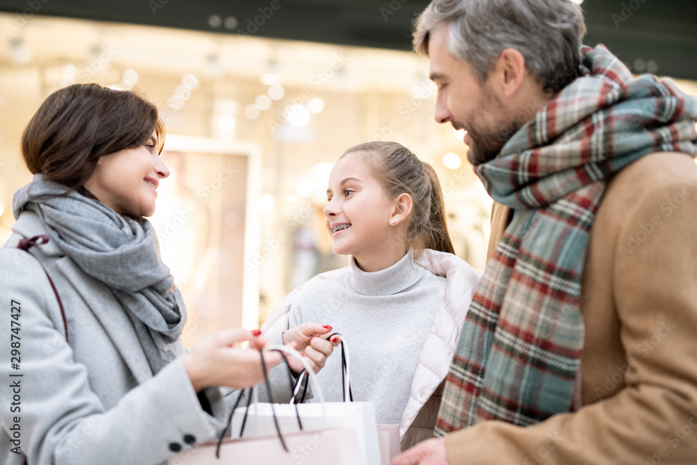 Happy family of three in casualwear discussing what they bought after shopping Happy family of three in casualwear discussing what they bought after shopping