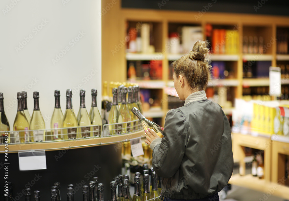 Woman choosing a wine, champagne at supermarket