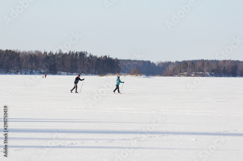 skier on a ski slope. winter ski on ice lake. winter hobby and sports. two peoples go skiing on ice lake