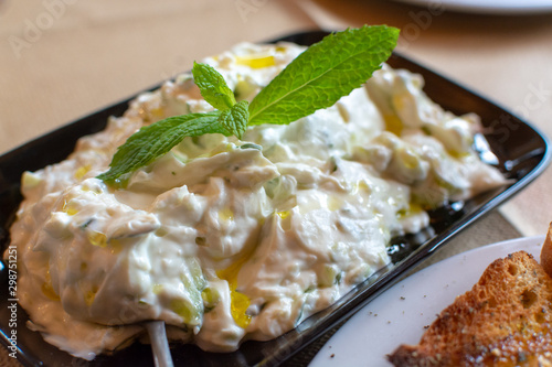 Tzatziki, dip or sauce from Southeast Europe and Middle East made of salted strained yogurt mixed with cucumbers, garlic, salt, olive oil, vinegar or lemon juice, and dill, mint, parsley and thyme. photo
