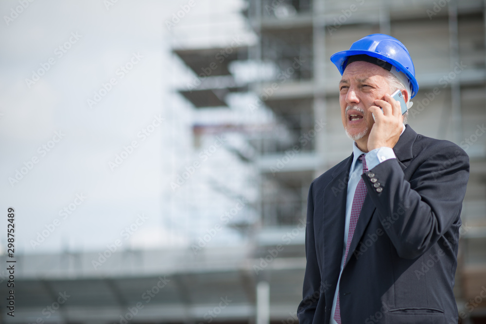 Architect manager talking on the cellphone in front of construction site Architect manager talking on the cellphone in front of construction site
