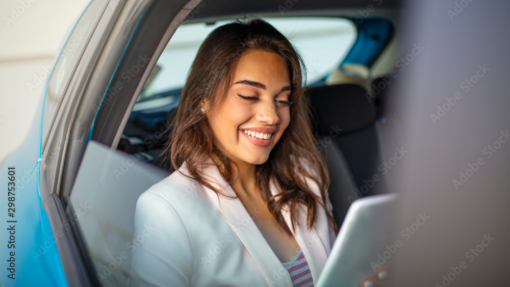 Businesswoman work with digital tablet computer and holding cup of coffee in back seat of luxury car. Beautiful business woman is using a smart phone and smiling while sitting on back seat in the car