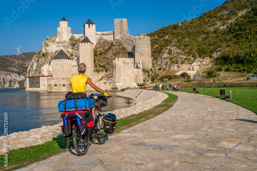 Biker tourist passing by newly restored Golubac fortress in Serbia along the Danube river photo
